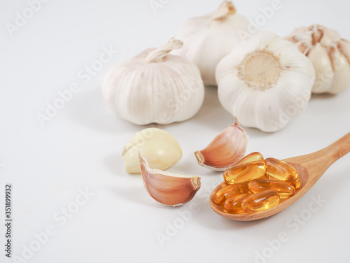 Capsule garlic oil in wooden spoon with fresh garlic, the benefit of garlic is prevent the occurrence of heart disease