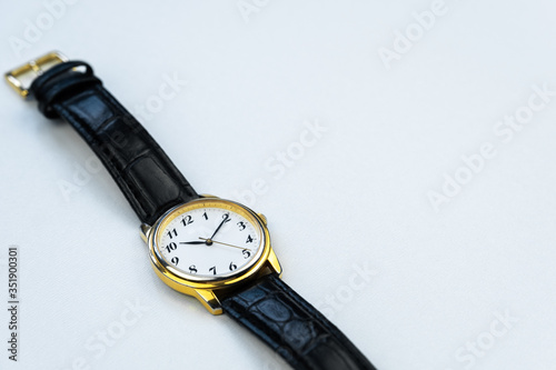 Retro golden wristwatch with Roman numerals isolated on white background close up.
