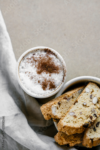 Freshly baked almond biscottis with cup of cappuccino on wooden background. Breakfast food concept.  photo