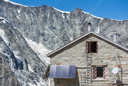 Horizontal snapshot of the alpine hut that is located above Zermatt, at the base of the Zinalrothorn, in Switzerland, solar panels installed on the walls as alternative source of energy photo