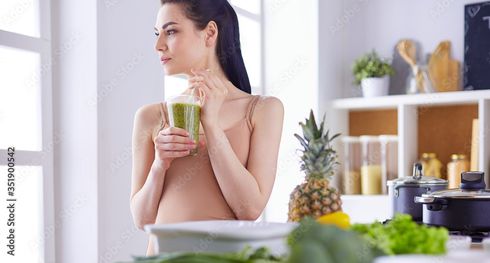 Young woman with glass of tasty healthy smoothie at table in kitchen Young woman with glass of tasty healthy smoothie at table in kitchen