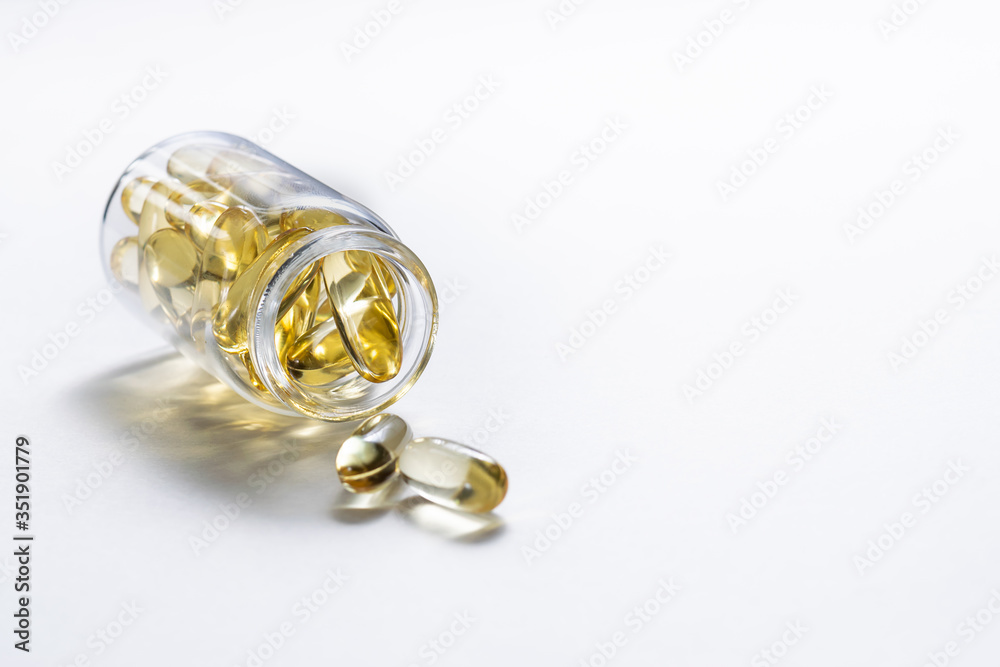 Cod liver oil capsules with vitamin D in glass bottle on white background with copy space for your text. Healthy lifestyle concept. Cod liver oil capsules with vitamin D in glass bottle on white background with copy space for your text. Healthy lifestyle concept.