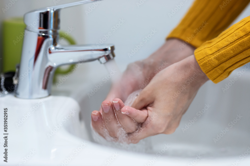 Young woman washing her hands with liquid soap under the water tap in the bathroom. Young woman washing her hands with liquid soap under the water tap in the bathroom.