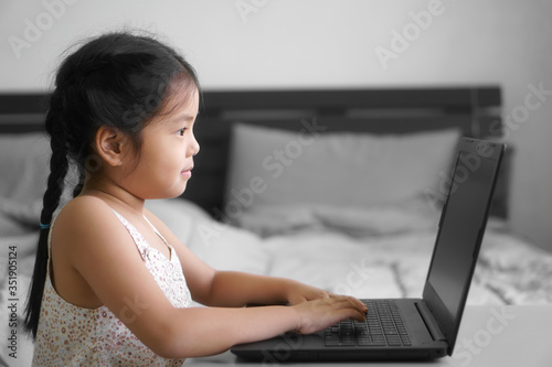 Asian child student or kid girl study online or work from home on computer notebook or play laptop by kindergarten school to primary education and happy smiling from coronavirus covid-19 and stay safe