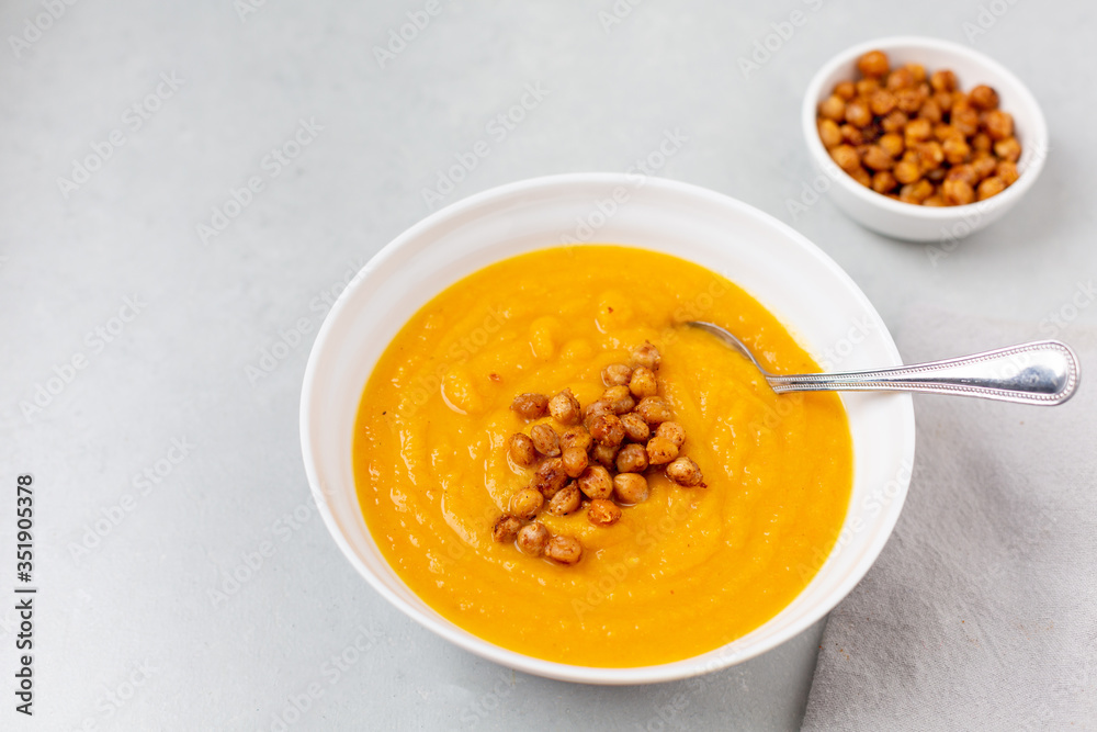 Homemade Butternut Squash Soup in White Bowl on Gray background; Roasted Chickpea Garnish Homemade Butternut Squash Soup in White Bowl on Gray background; Roasted Chickpea Garnish