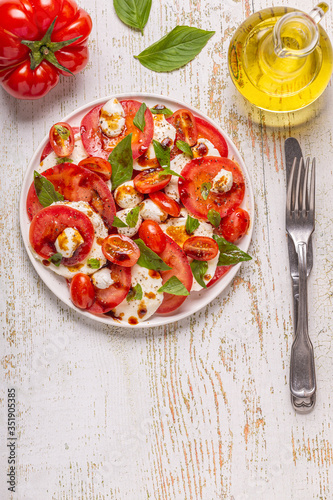 Italian caprese salad with sliced tomatoes, mozzarella cheese, basil, olive oil, balsamic vinegar.