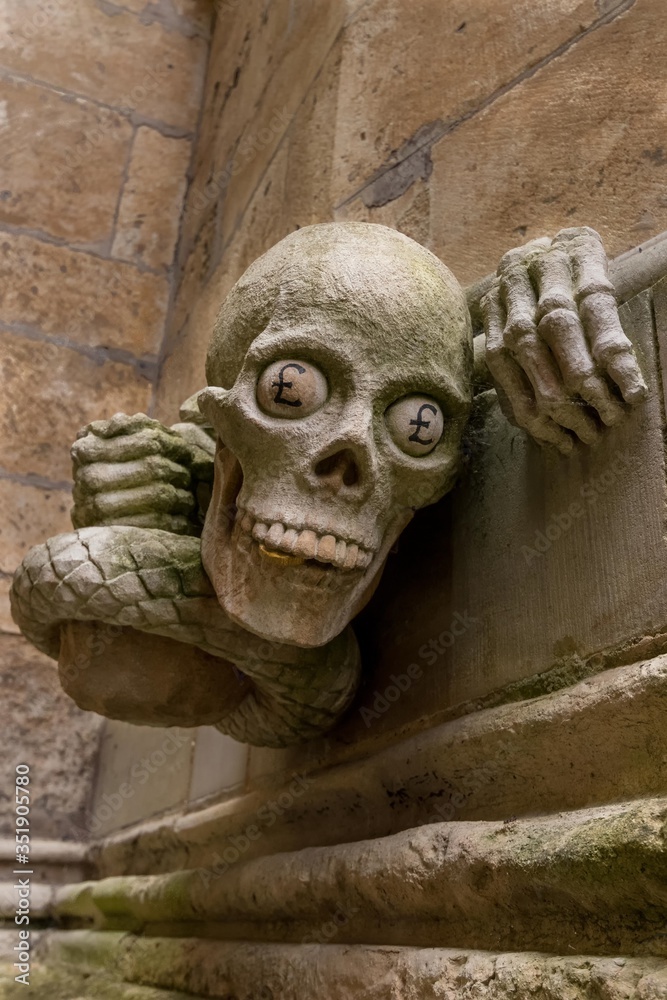 mit englischen Pfundzeichen bemalte Gargoyle an der Außenwand der Kathedrale von Lincoln als Symbol gegen die Geldgier mit englischen Pfundzeichen bemalte Gargoyle an der Außenwand der Kathedrale von Lincoln als Symbol gegen die Geldgier