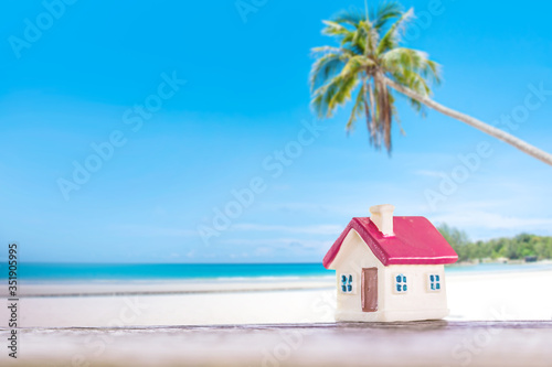 miniature house with red roof on tropical sand beach over blurred clear sky on day noon light.Image for property real estate investment concept. 