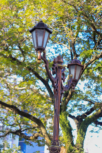 Street lights against a background of blue sky and trees