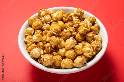 Plate with caramel popcorn on a red background