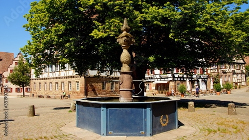 alter Brunnen im Klosterhof von Maulbronn unter grünem Baum umgeben von alten Gebäuden