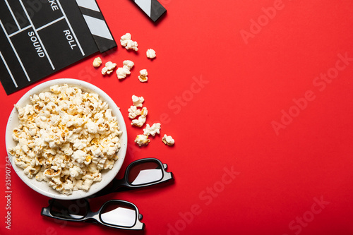 Fotografía Plate with popcorn and movie clapper on a red background