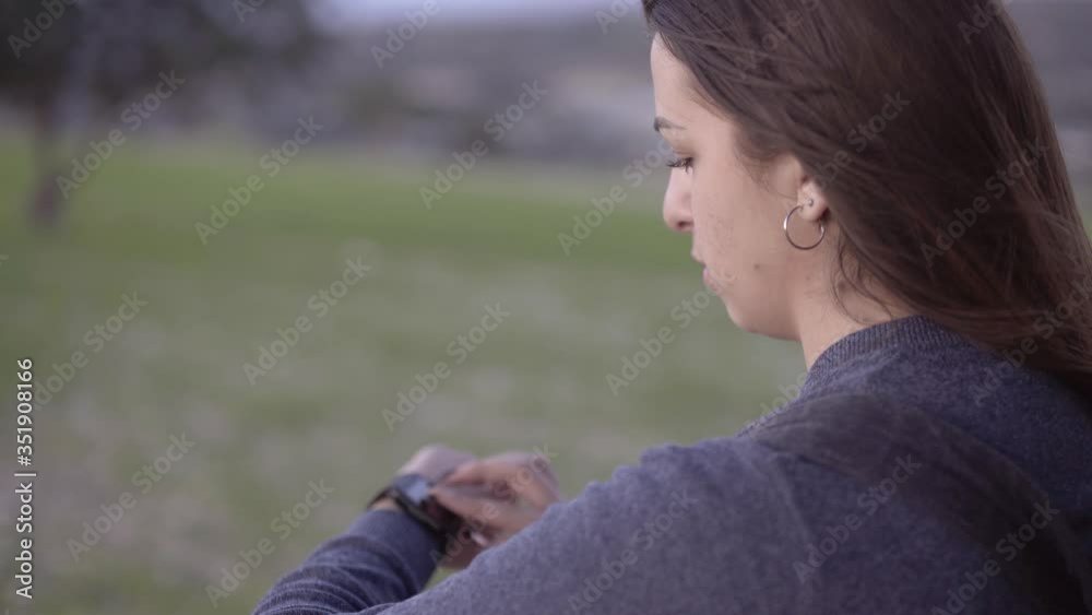 Young woman using smartwatch to check text messages outdoors Young woman using smartwatch to check text messages outdoors