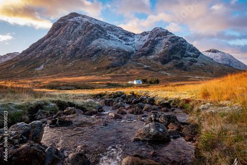Cottage overlooked by Etive Mor, Glencoe in the dramatic highlands of scenic Scotland, fantastic adventure travel destination or holiday vacation to view picturesque scenery at sunrise or sunset