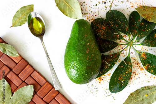 avocado, avocado oil, seasoning, green leaves. All ingredients for a salad of eternal youth. On white background