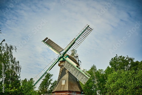 Historic and restored windmill in Berlin, Germany, between trees in spring.