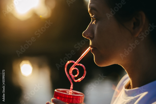 Portrait of a girl with pensive look which is drinking a drink through a bright cocktail stick photo