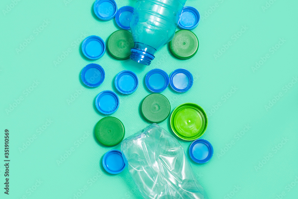 Composition of plastic bottles and plastic bottle caps on green background with space for text Composition of plastic bottles and plastic bottle caps on green background with space for text