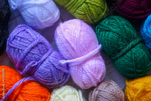 Close up of small balls of yarn in different colours shot from above. Top view, flat lay.