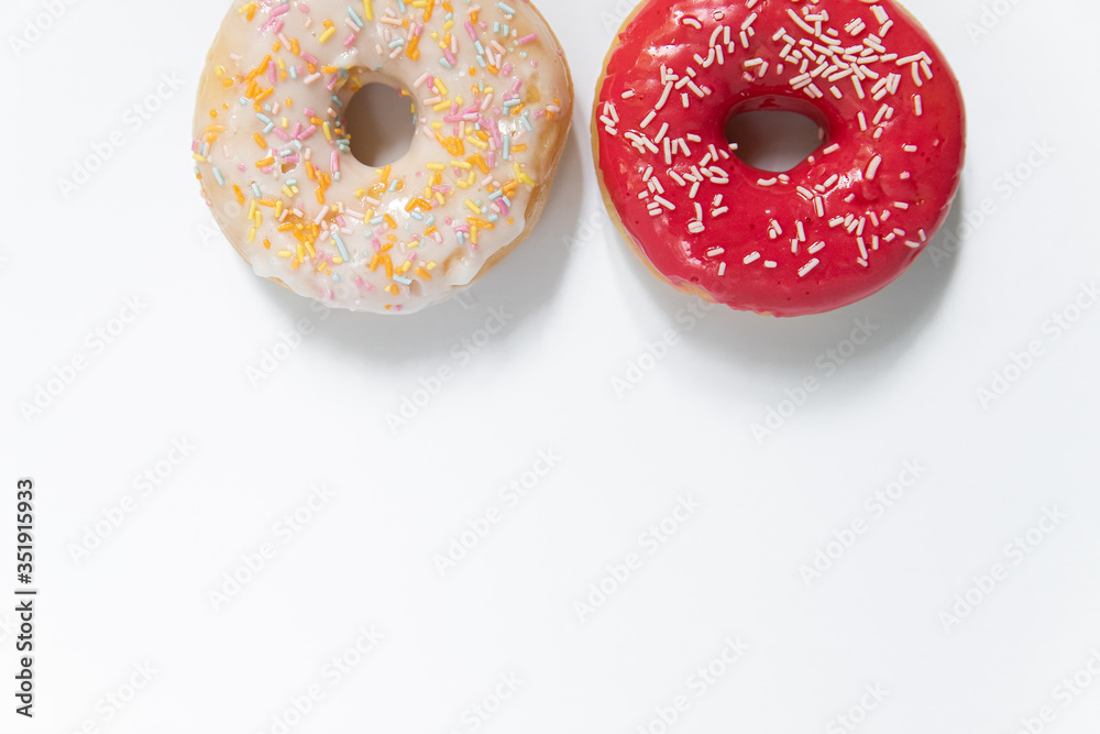 Donut day. Two bright colored donuts with colorful sprinkles on white background. Copy space, close-up