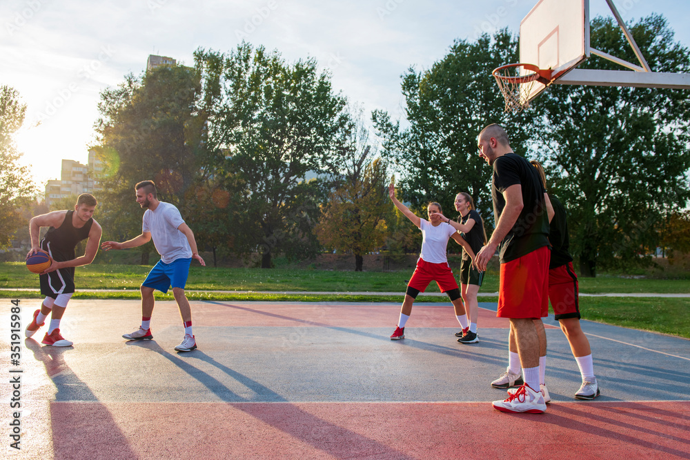 Obraz premium Group Of Young Friends Playing Basketball Match