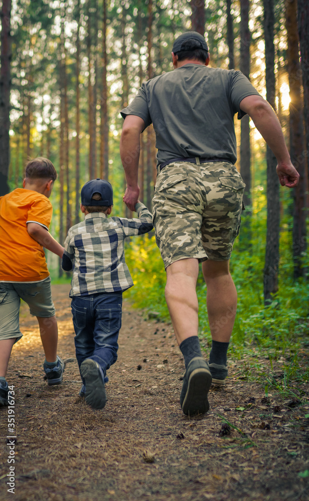 father and two children running in the forest father and two children running in the forest