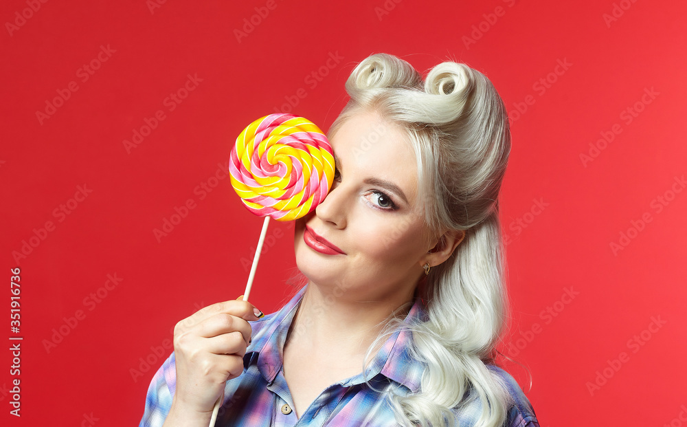 beautiful blonde with a big candy, posing on a red background