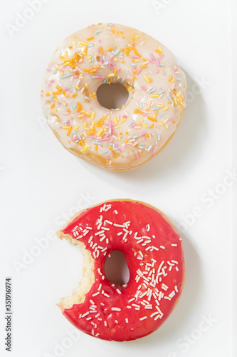 Donut day. Bitten colored donuts with colorful sprinkles on white background. Copy space, close-up