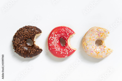 Donut day. Bitten colored donuts with colorful sprinkles on white background. Copy space, close-up