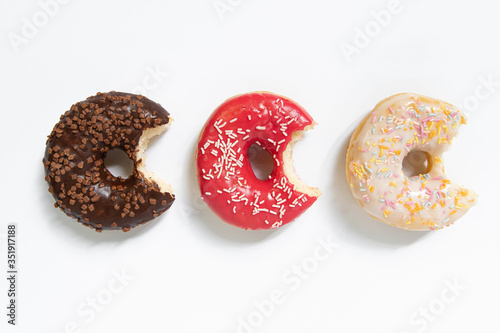 Donut day. Bitten colored donuts with colorful sprinkles on white background. Copy space, close-up