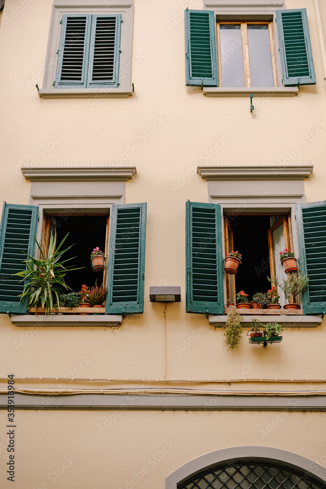 The facade of an apartment building in Florence, Italy, with green wooden shutters.