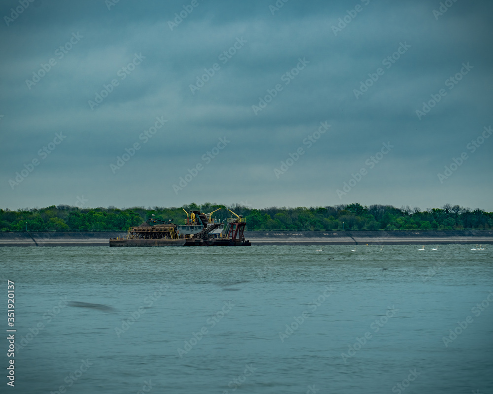 Fototapeta premium A barge in the middle of the lake on a rainy day, birds are flying around.