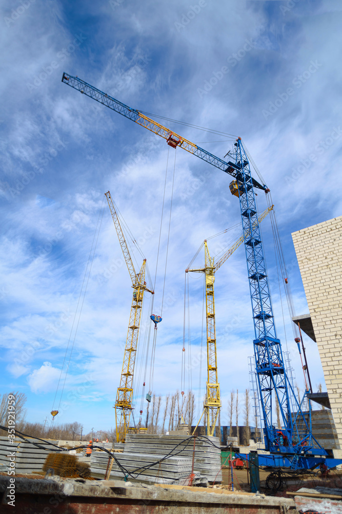 Photos of high-rise construction cranes and an unfinished house against a blue sky. Photographed on a wide angle lens