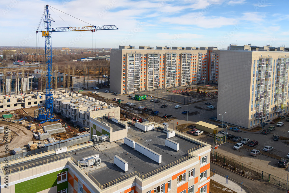 Photos of high-rise construction cranes and an unfinished house against a blue sky. Top view of the construction site.