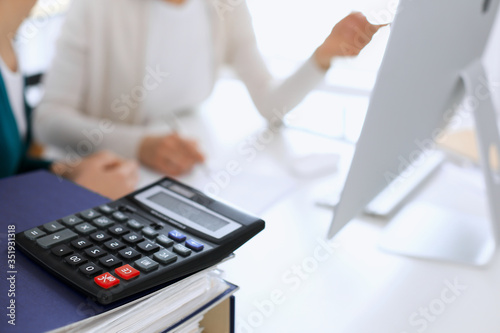 Calculator and binders with papers are waiting to be processed by business woman or bookkeeper working at the desk in office back in blur. Internal Tax and Audit concept © Iryna