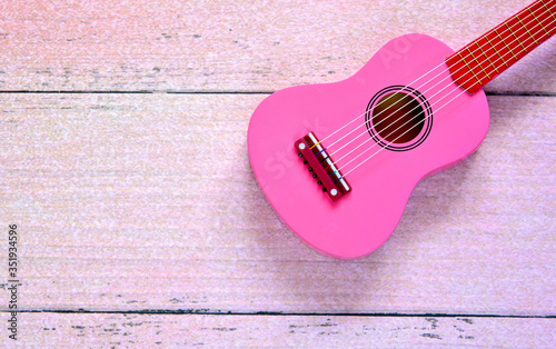pink wooden retro guitar for girl laying on pink wooden floor