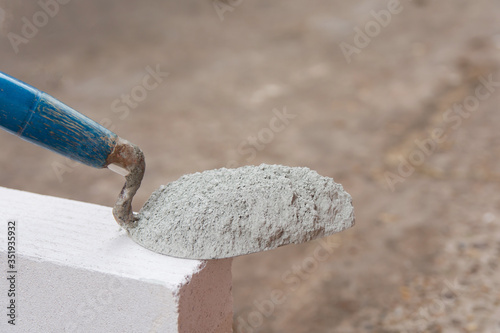Cement powder or mortar with  trowel put on the Lightweight Concrete brick for construction work..