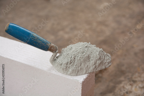 Cement powder or mortar with  trowel put on the Lightweight Concrete brick for construction work..