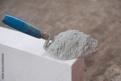 Cement powder or mortar with  trowel put on the Lightweight Concrete brick for construction work..