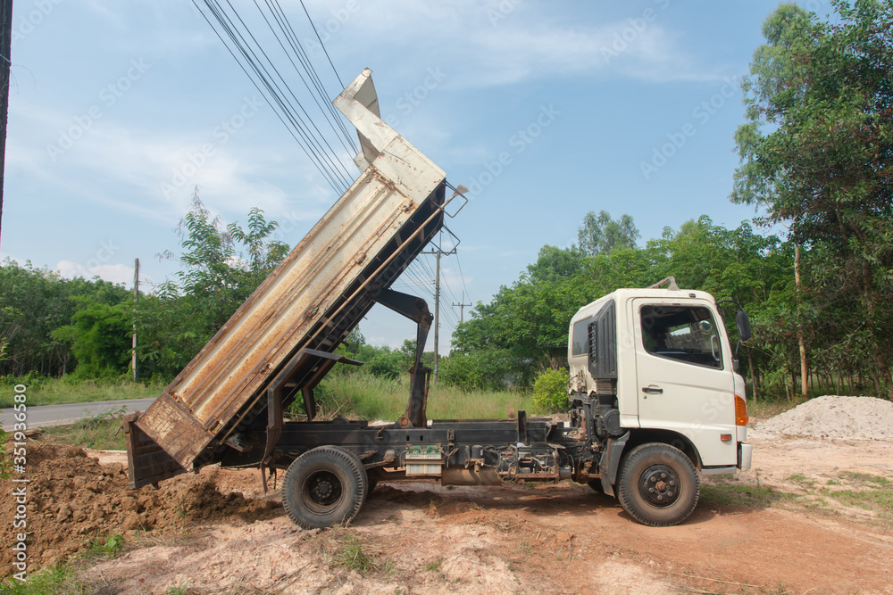 Dump truck unloading soil at construction site.
