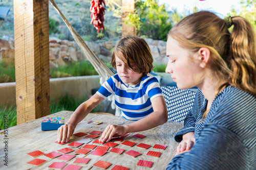 teen sister playing memory game on outdoor table with her 6 year old brother