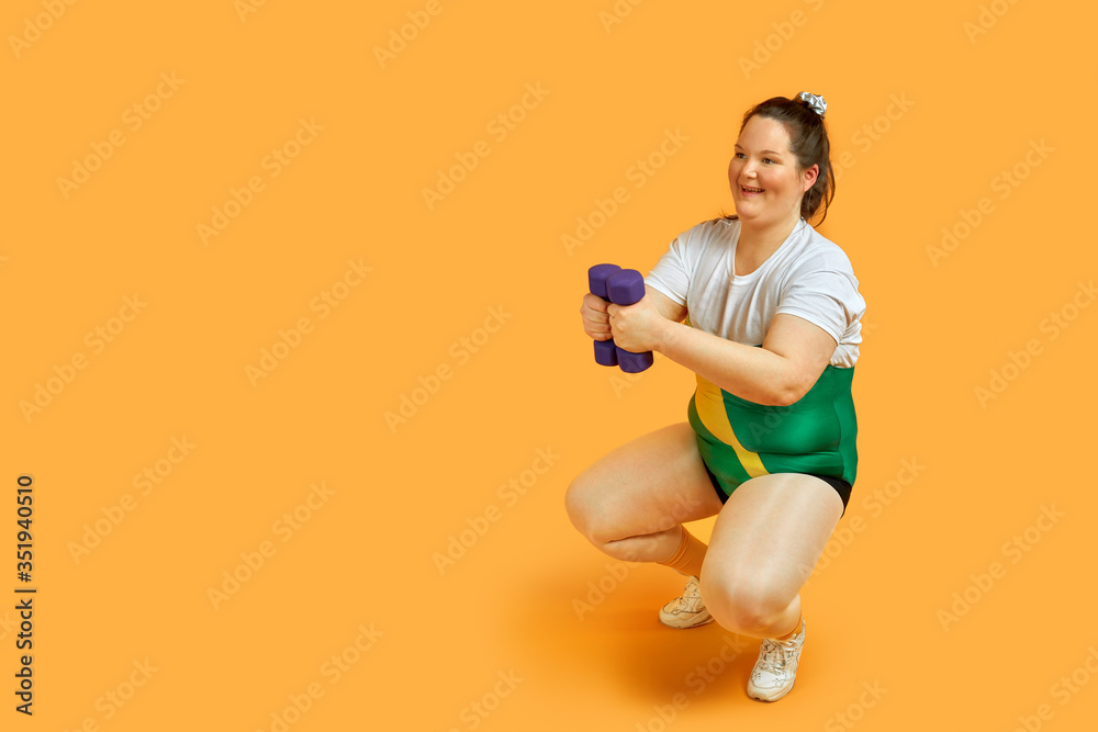 A fat girl goes in for sports, crouches, shakes her ass in sportswear with dumbbells in her hands. A fat girl goes in for sports, crouches, shakes her ass in sportswear with dumbbells in her hands.