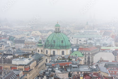 Cityscape of Vienna with Peterkirche (St. Peter's church) in a snowy day, in the old town of Vienna, Austria.  View at the tower of St. Stephen's Cathedral.