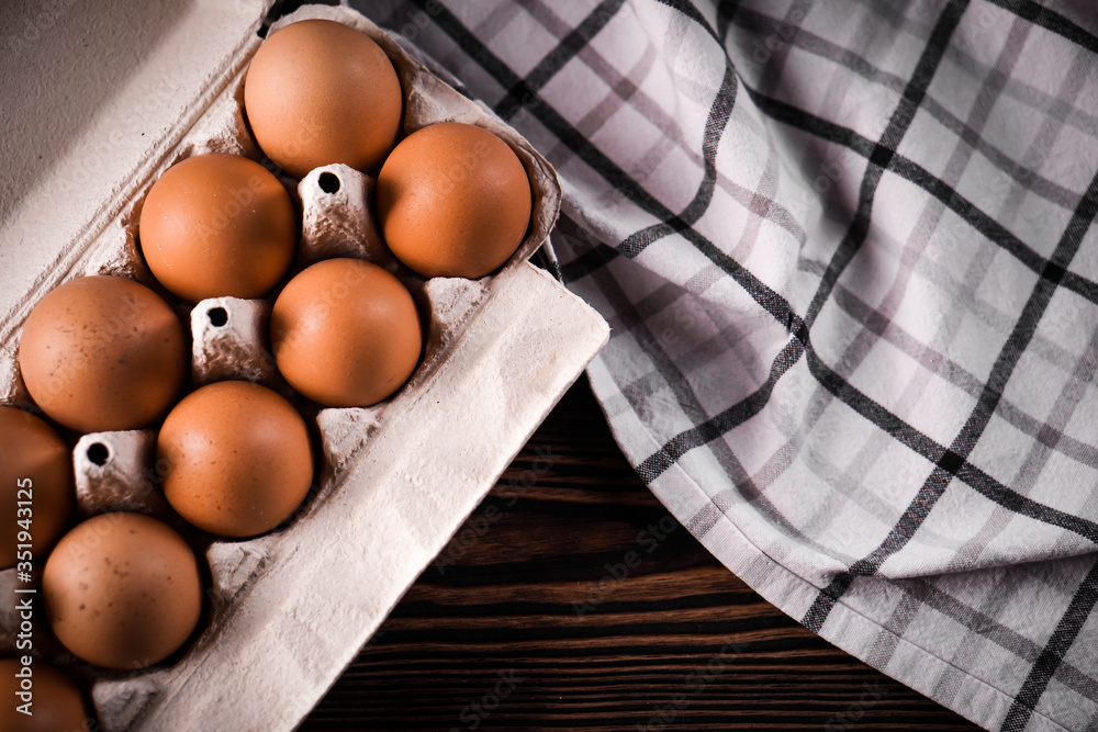 Detail close-up of chicken eggs in egg box on the old brown wooden background. Detail close-up of chicken eggs in egg box on the old brown wooden background.