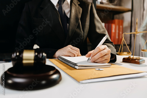 Justice and law concept.Male judge in a courtroom with the gavel, working with, computer and docking keyboard, eyeglasses, on table in morning ligh