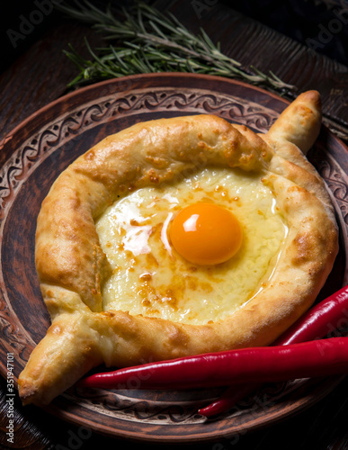Hospitable Georgian cuisine. Khachapuri with cheese and egg on a wooden background