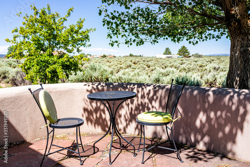 Backyard patio terrace garden with chairs and table in Ranchos de Taos valley and green landscape in summer sunny day and nobody