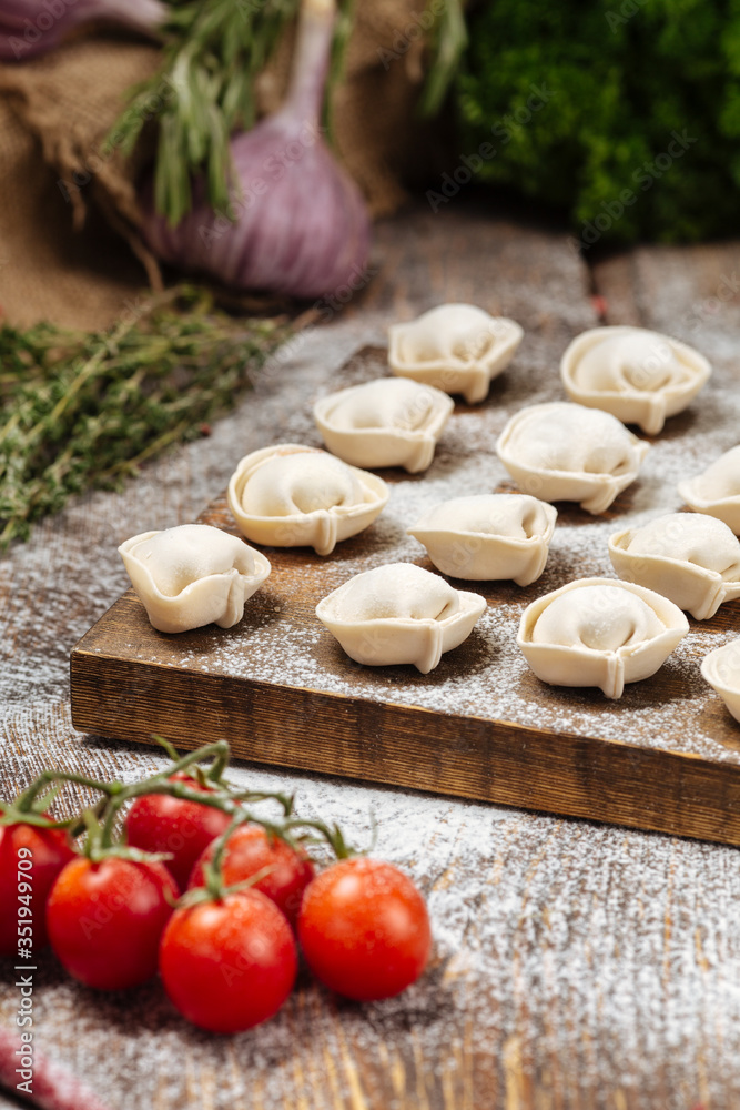 Semi-finished pelmeni dumplings on wooden board Semi-finished pelmeni dumplings on wooden board