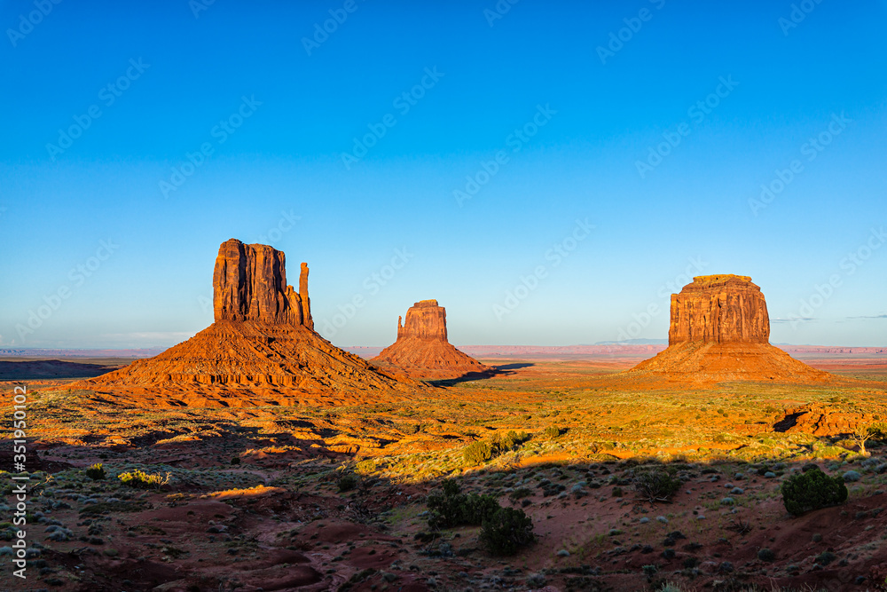 Wide angle view of famous buttes and horizon in Monument Valley at sunset vibrant colorful light in Arizona with orange rocks