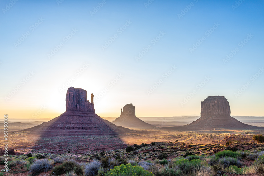 Panoramic view of merrick mitten buttes and horizon in Monument Valley at sunrise colorful light and sun beam rays behind rocks in Arizona